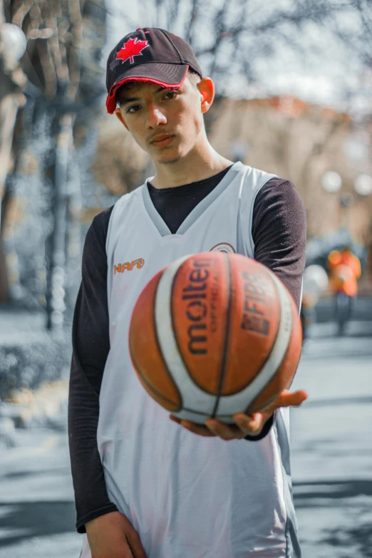 young man holding a basketball outside in front of a tree