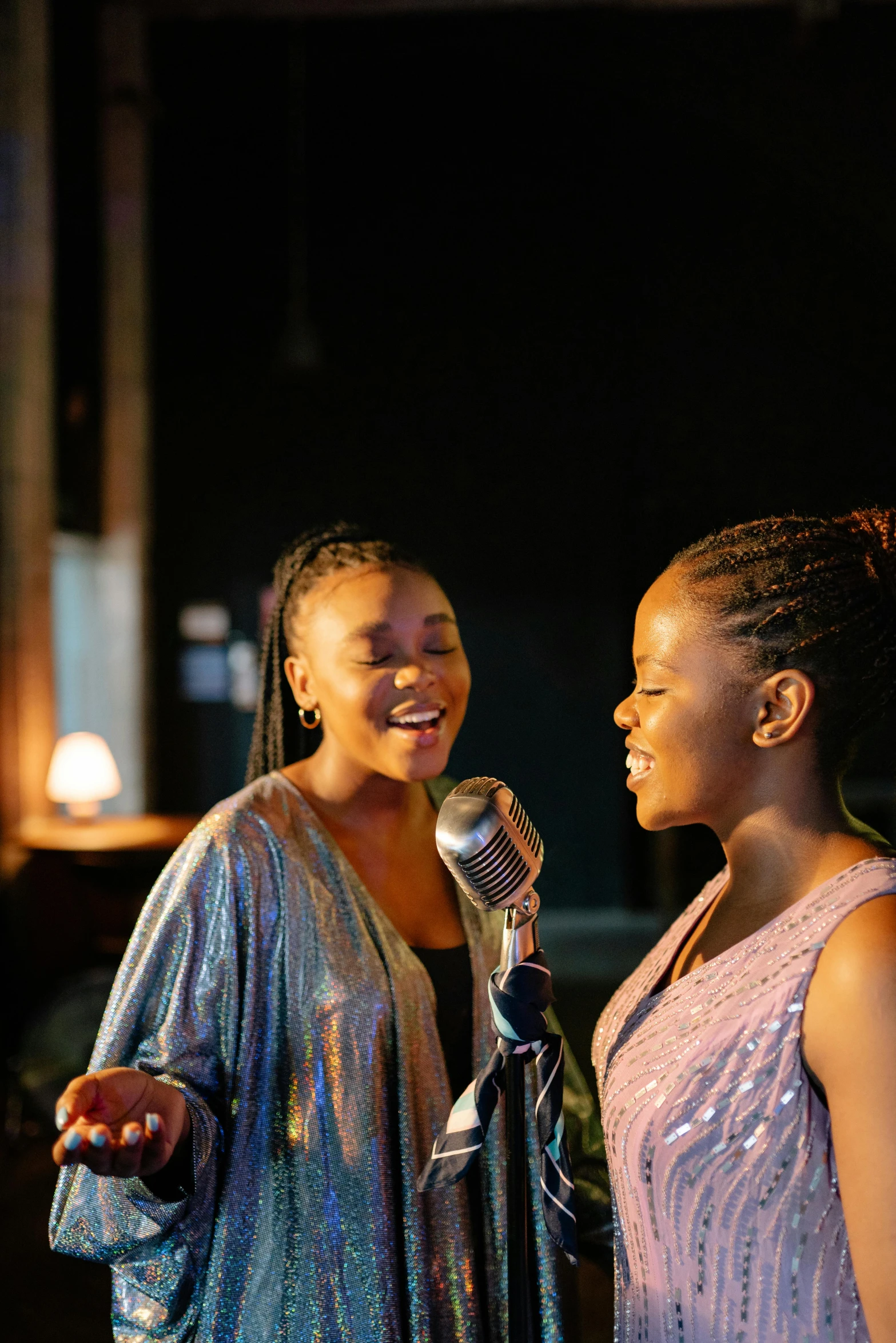 two women singing into microphones while one is smiling