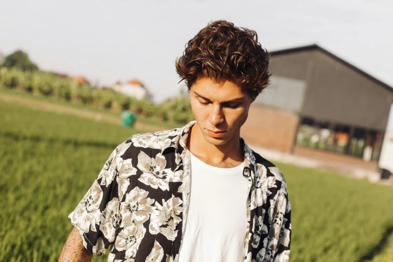 young man in shirt looking down at cell phone