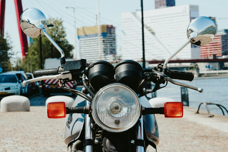 close up of a motorcycle headlight on brick pavement next to water