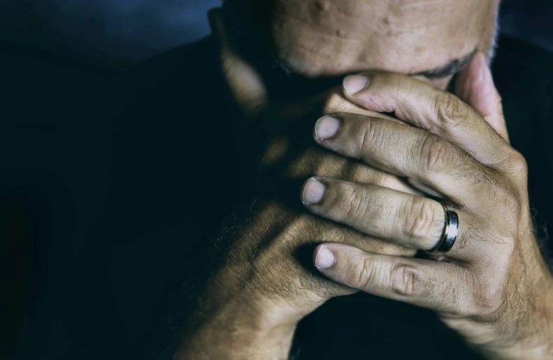 a man is holding his hands together while covering his face