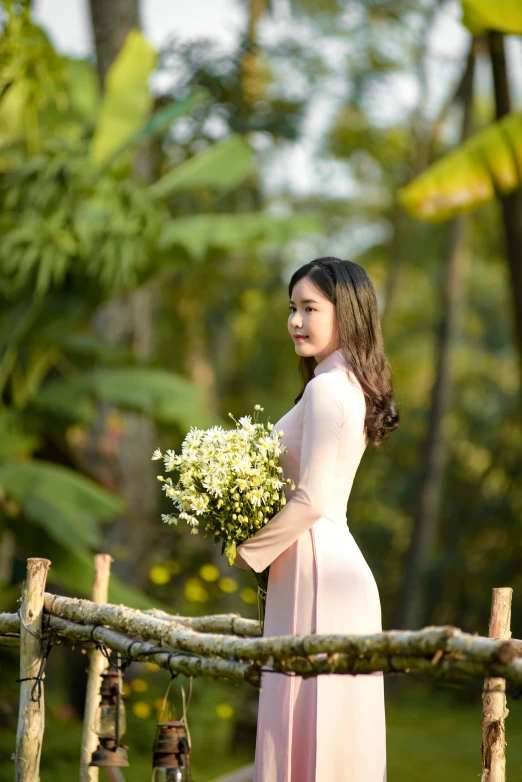 a woman holding a bouquet standing next to a fence