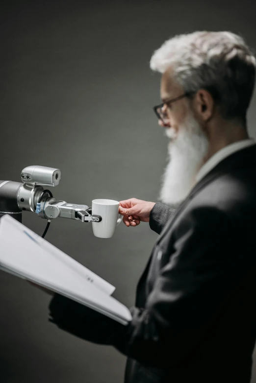 a man in a suit standing with a coffee cup next to a microphone