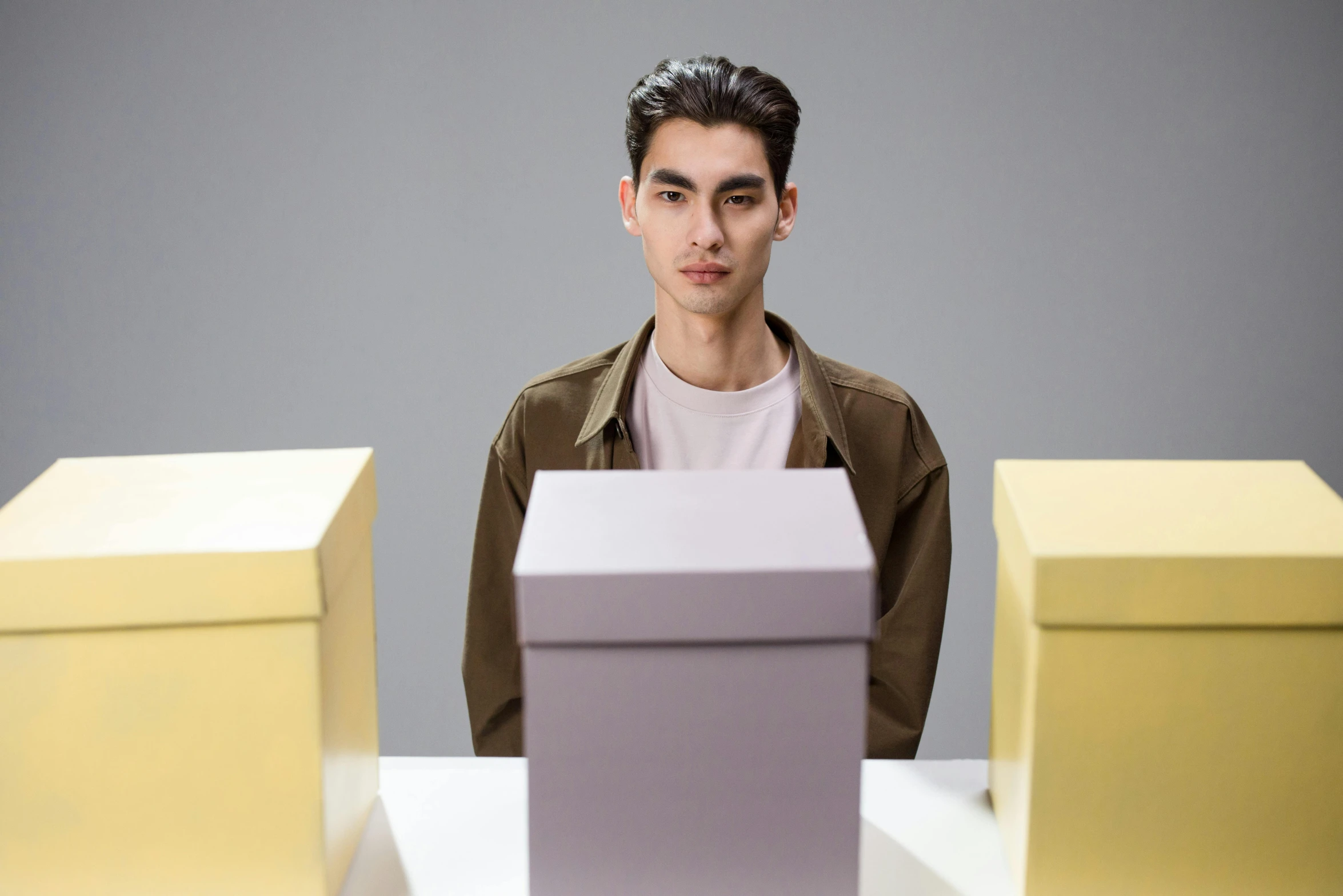 man standing behind two colored boxes on top of a table