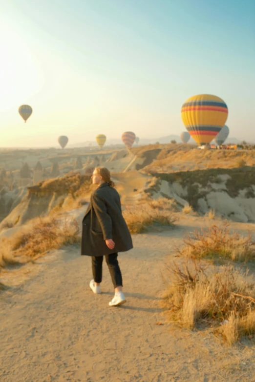 a person is standing on a dirt path near some  air balloons