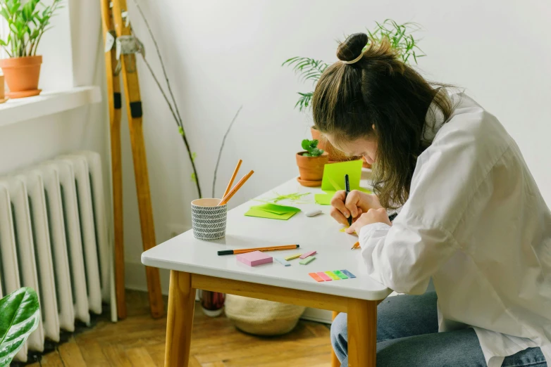 a woman sitting at a table painting some pieces of paper