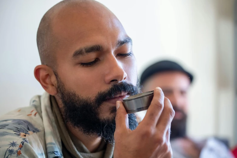 a man with a beard smoking a pipe and another man sitting down