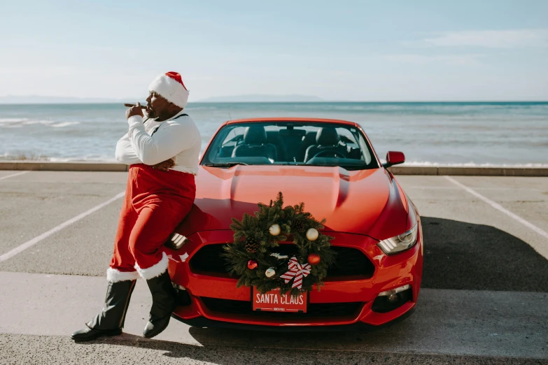 a man standing next to a red car with a wreath on it