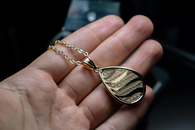 a close up of a person holding a small necklace