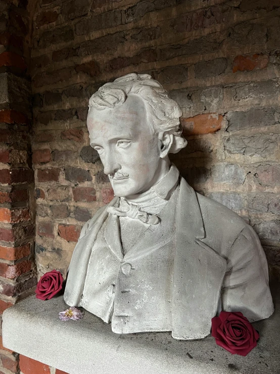 a white plaster bust of a man with roses on his lap