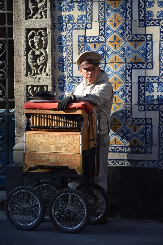 a person stands near a small cart with many wheels on a sidewalk