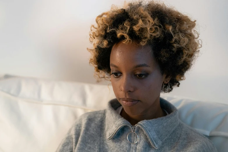 the girl is sitting on a couch with curly hair