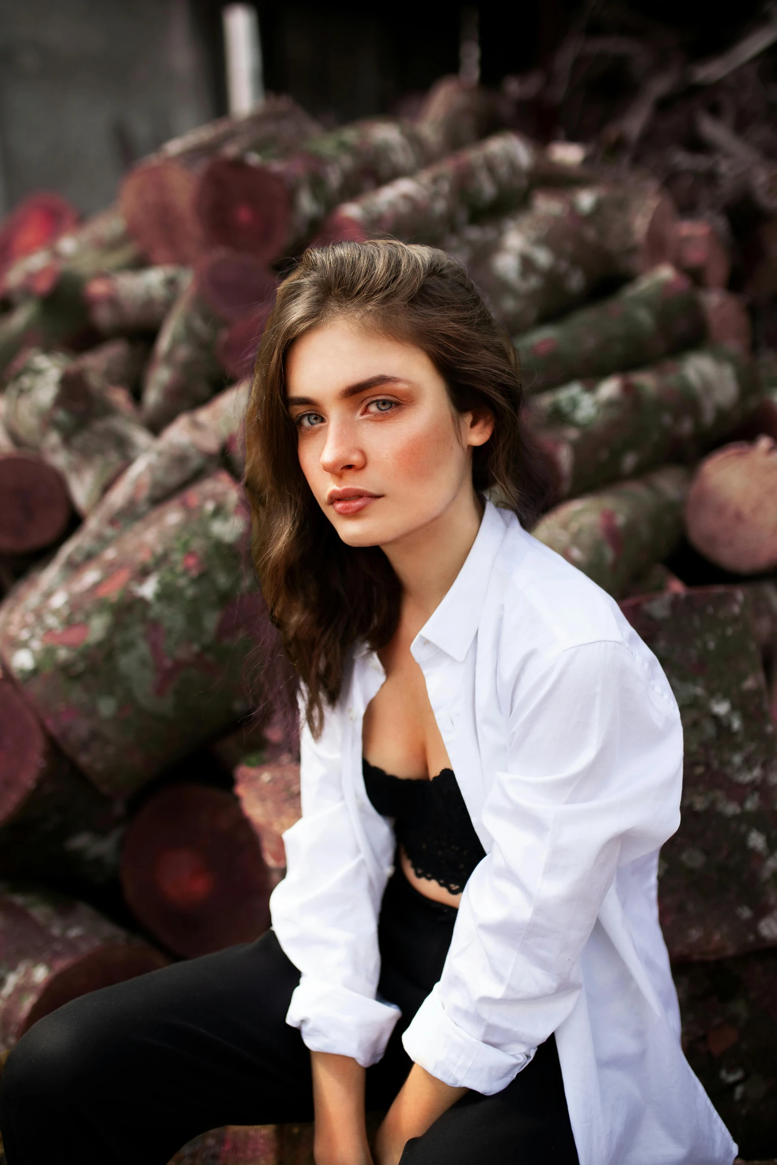 a woman in white shirt sitting on log pile