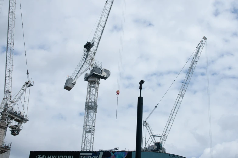 crane construction work atop a stadium under cloudy skies