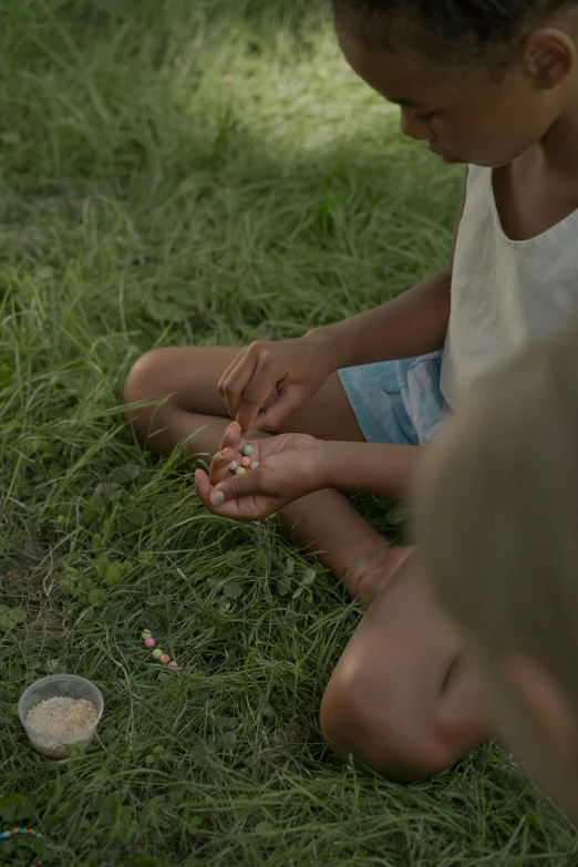 a child on the grass holds a toothbrush and feeds it