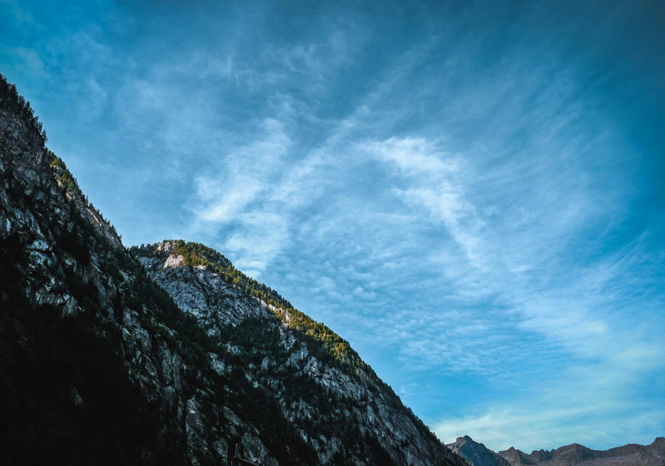 a mountain side view of a cloud covered sky