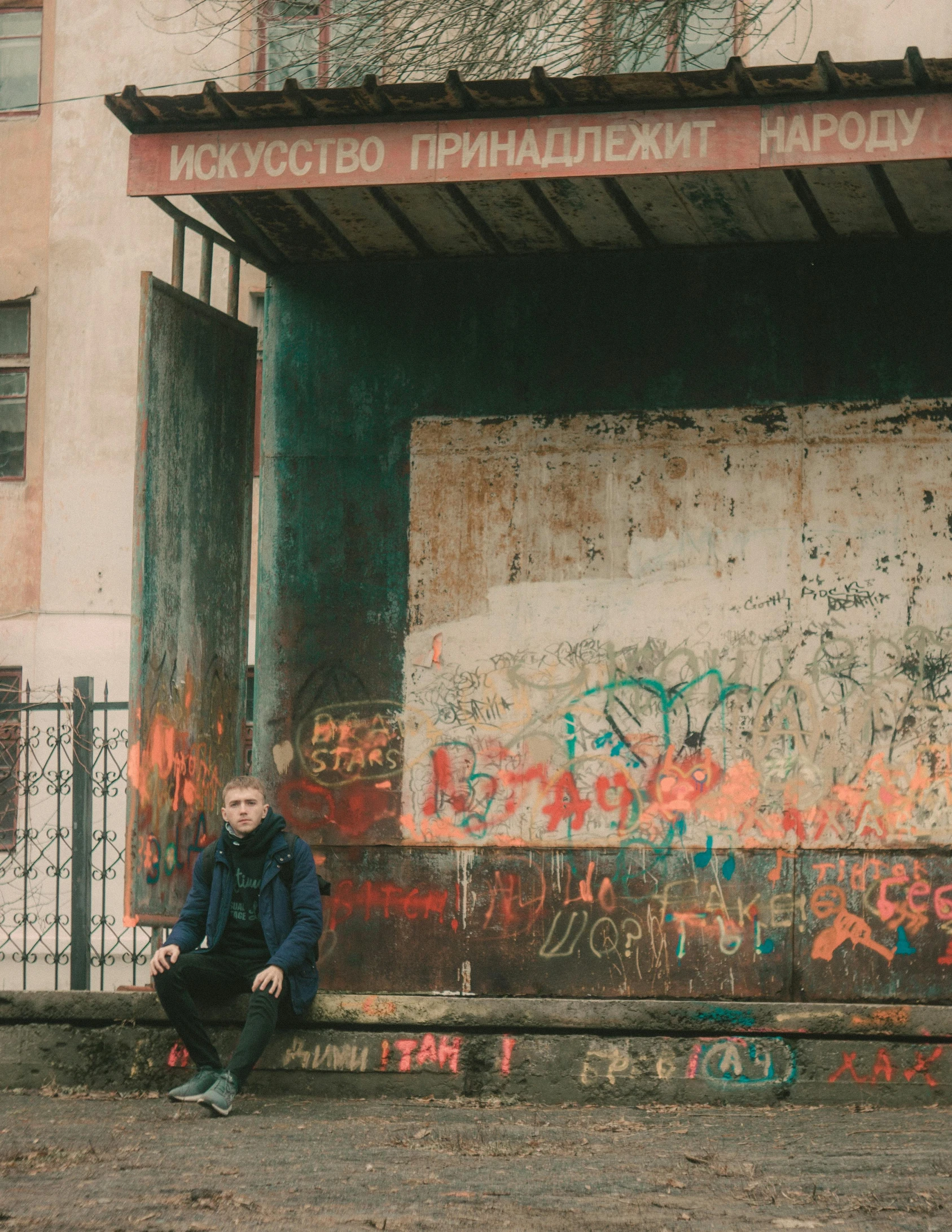 man sitting on ledge outside with graffiti in old city