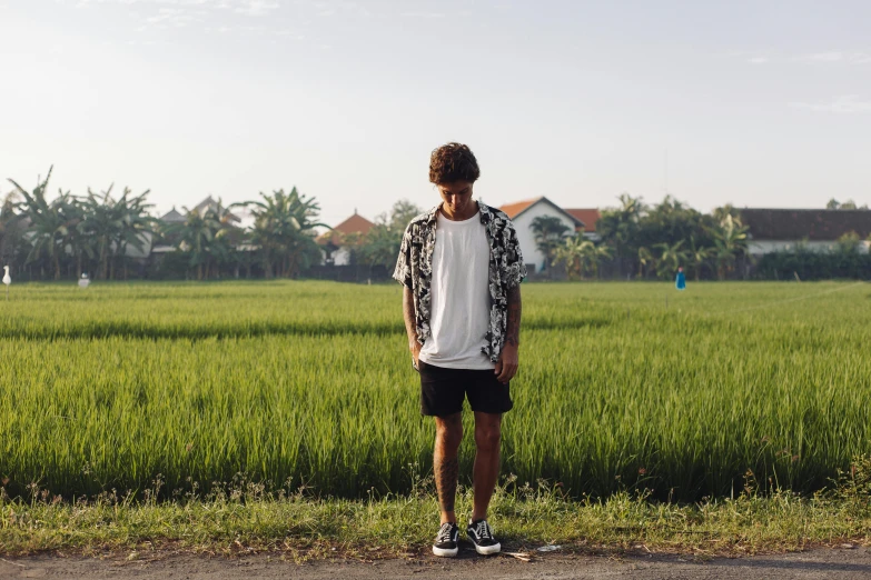 the boy is standing in front of a green field