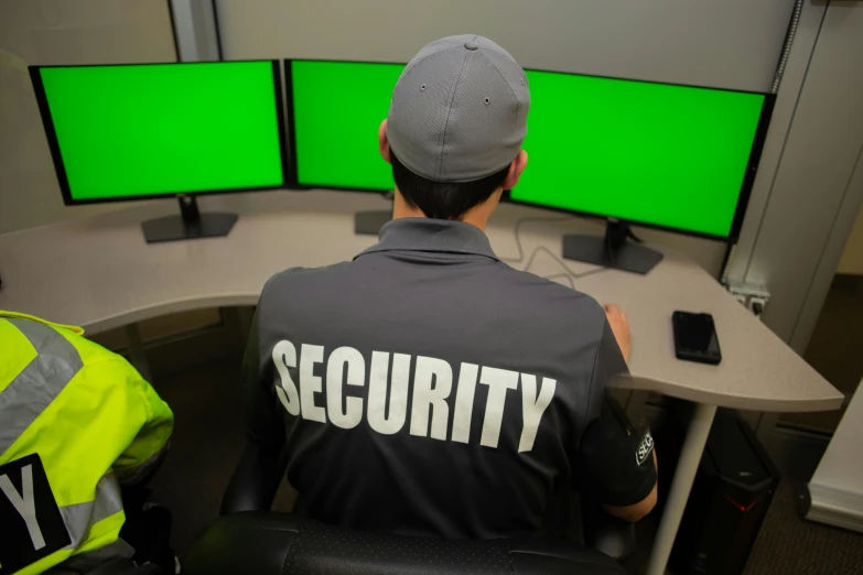 a security officer watching four monitors while sitting in front of them