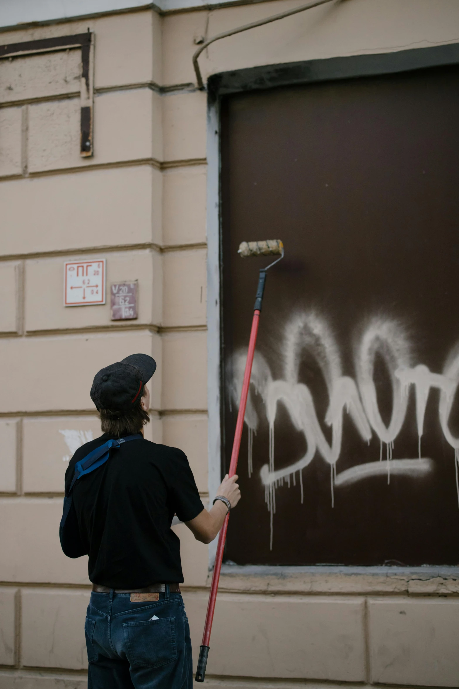 a man cleaning graffiti off of a door with a paint roller