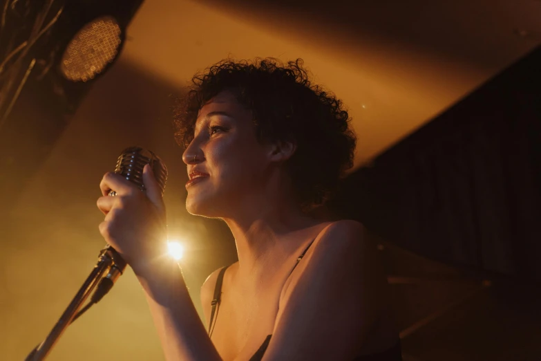 a girl standing in front of a microphone, singing