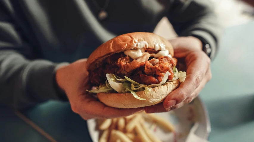 a person holding a large sandwich with meat and onions