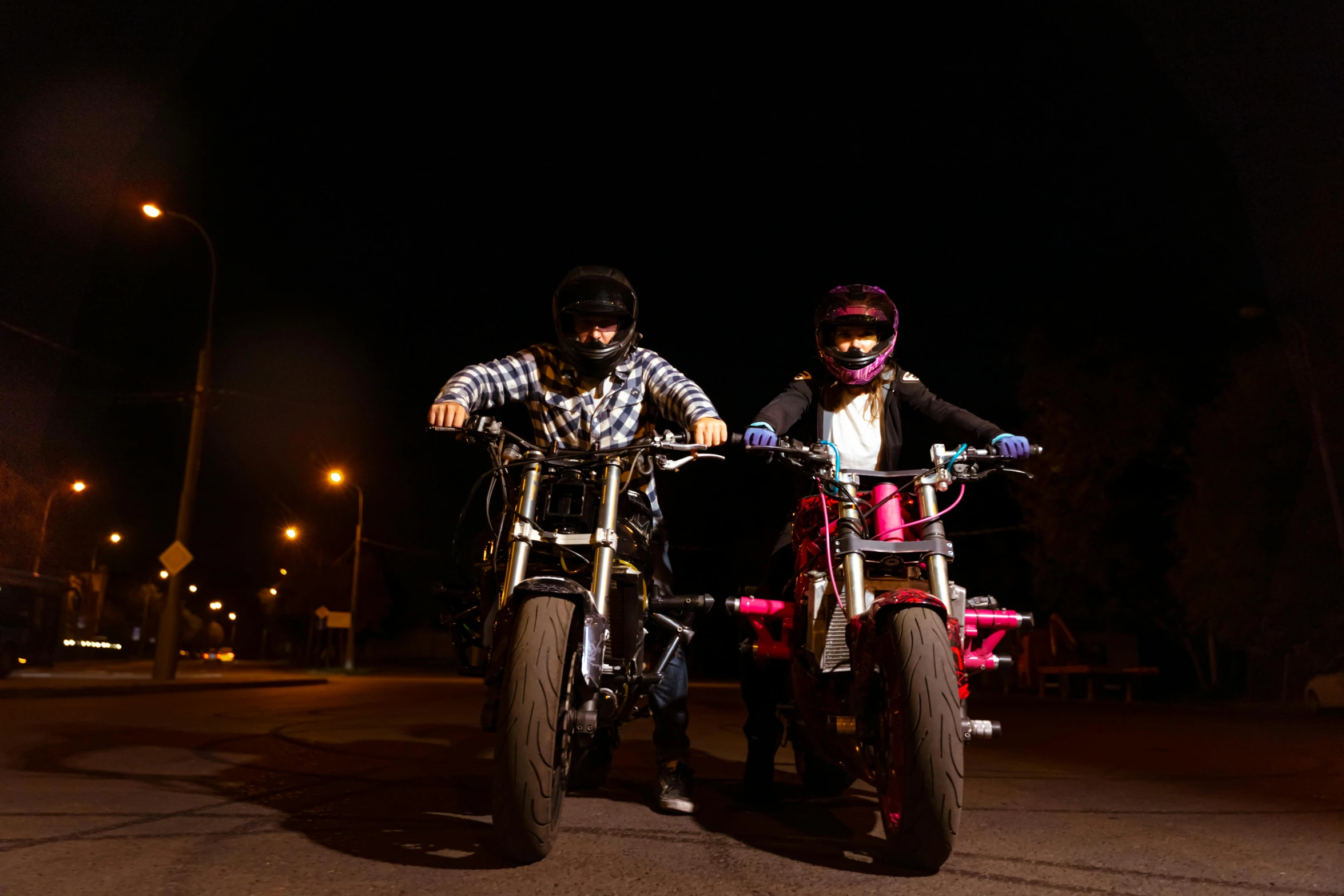 two people riding bikes at night with street lights