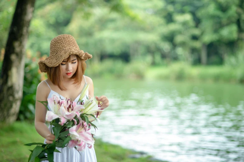 woman in dress with flower arrangement next to a lake