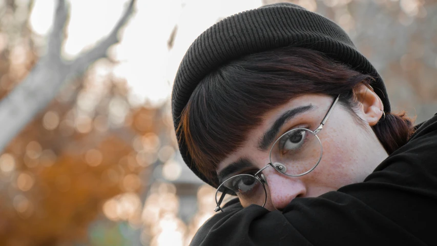 a woman with glasses and a knitted hat holding a cell phone