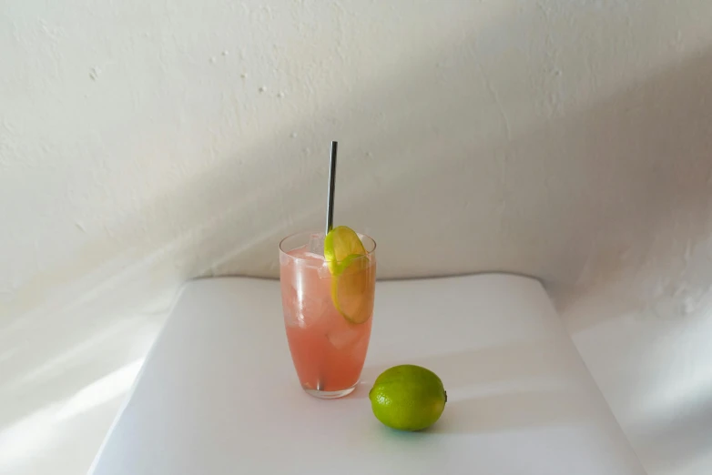 a pitcher of water sits next to an uncut lime on a white table