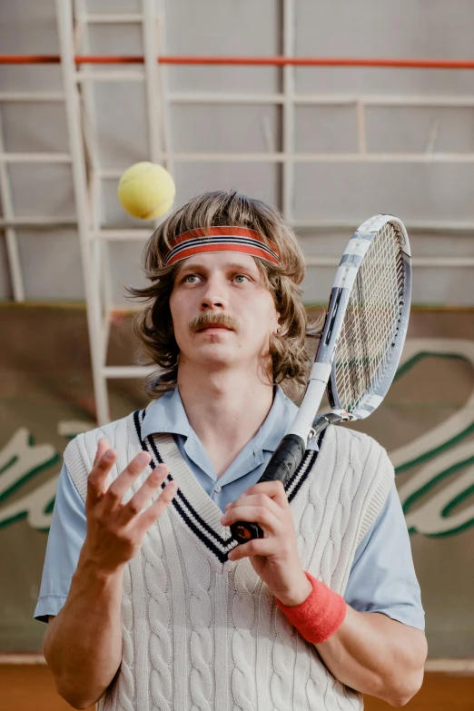 a young man is wearing a hat and holding a tennis racket