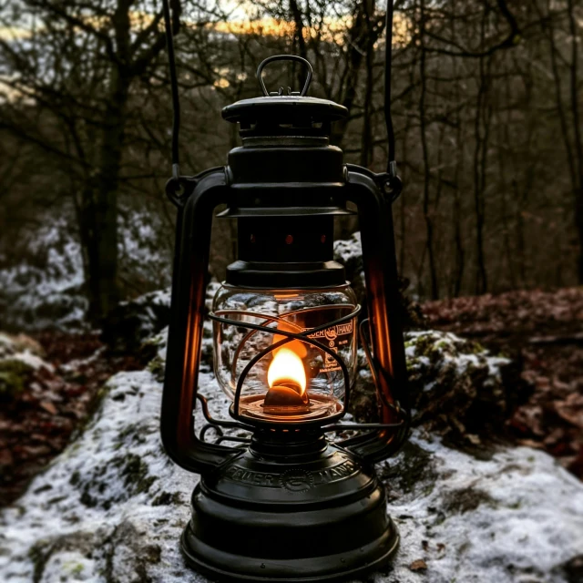 a lit lantern sitting on top of snow covered ground
