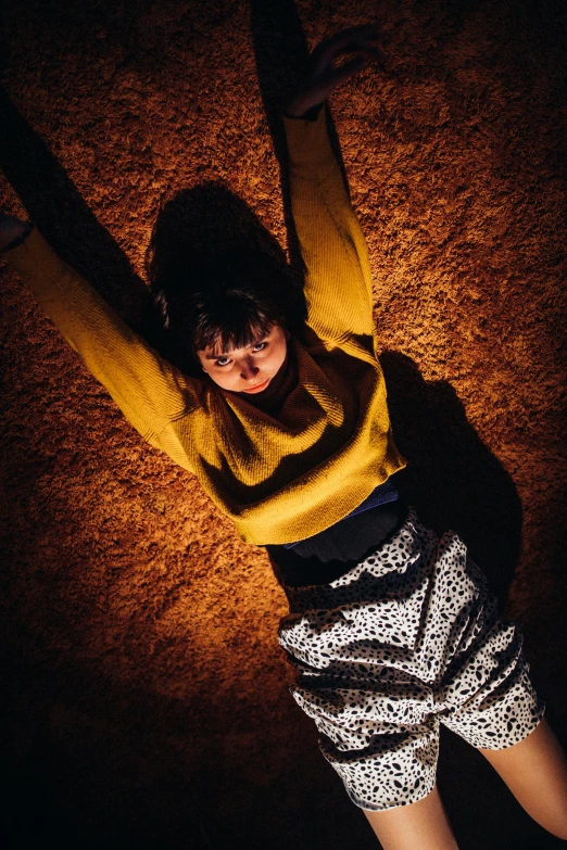 a woman is standing in a brown field with her arms up