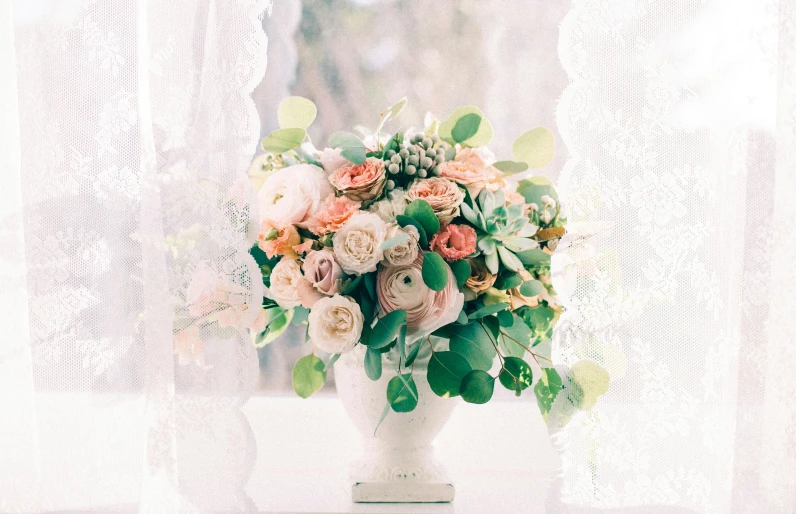 a vase sitting on a windowsill with roses and greenery