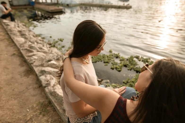 two girls are standing next to the water