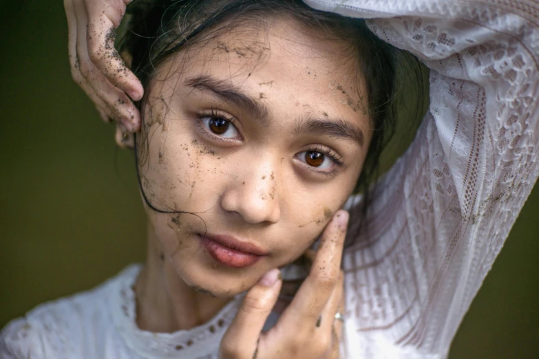 a woman with freckles and brown eyes has her hand under the forehead