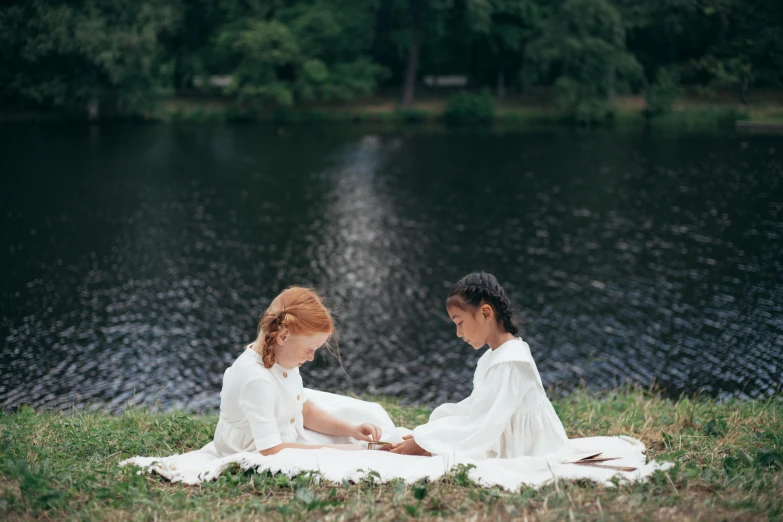 two s sitting on a blanket by a lake