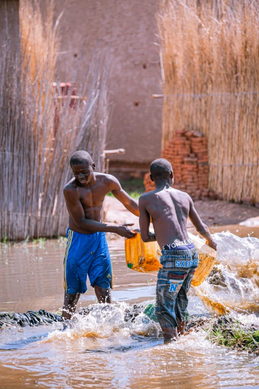 two men play in a lake while one pulls a net