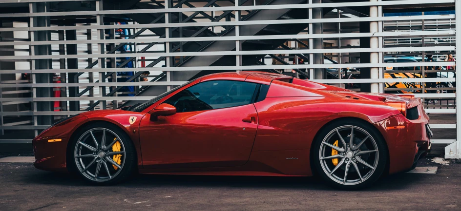 a red car parked next to a tall white wall