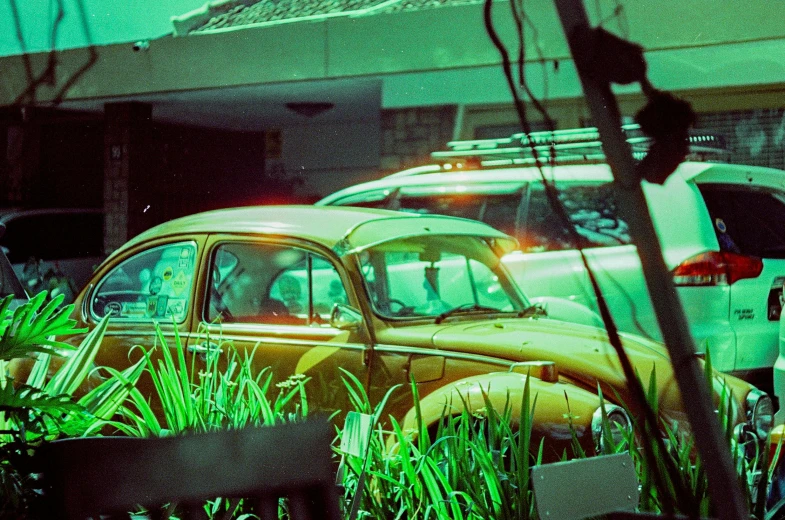 a couple of old yellow cars sitting parked in a field