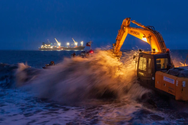 a yellow construction vehicle on top of a wave