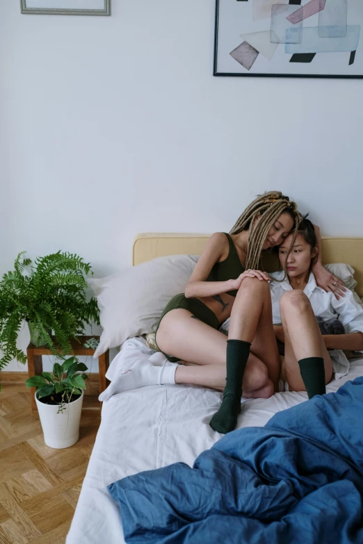 two beautiful women sitting next to each other on a bed