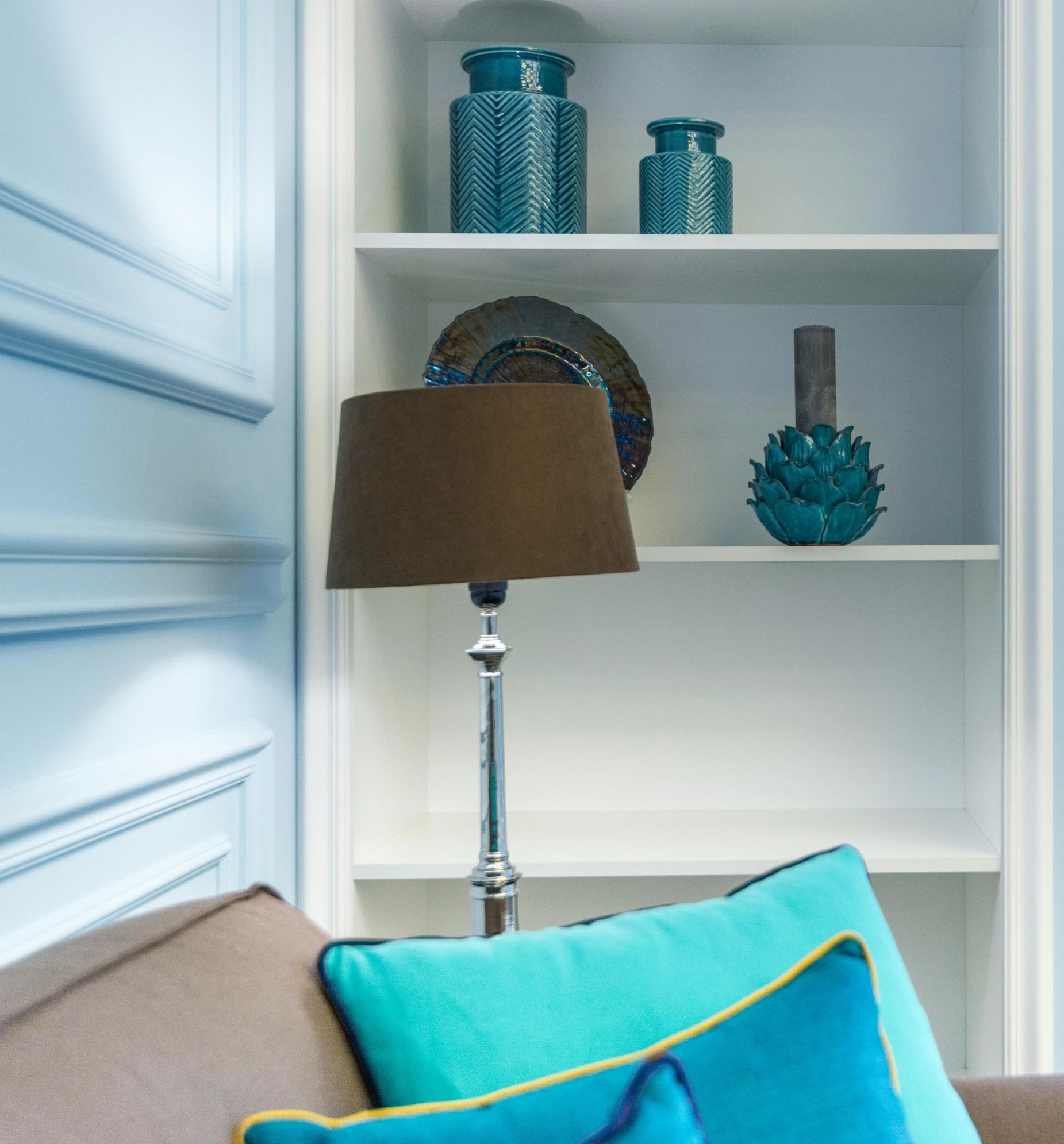 the corner shelves in this living room hold blue vases and other items