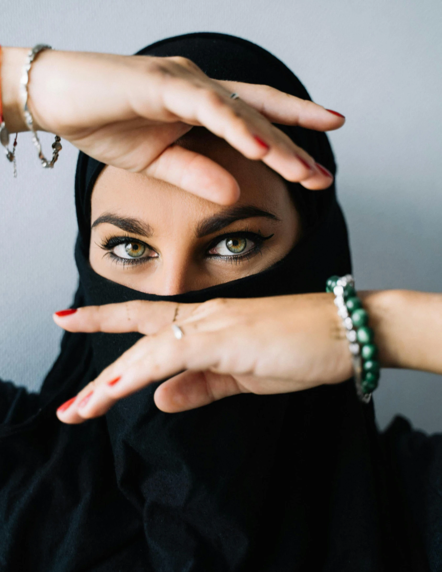 a woman is wearing a black head scarf and has her fingers up