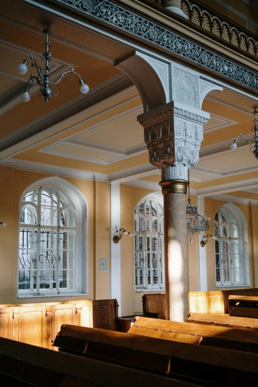 an empty room with wooden pews and windows