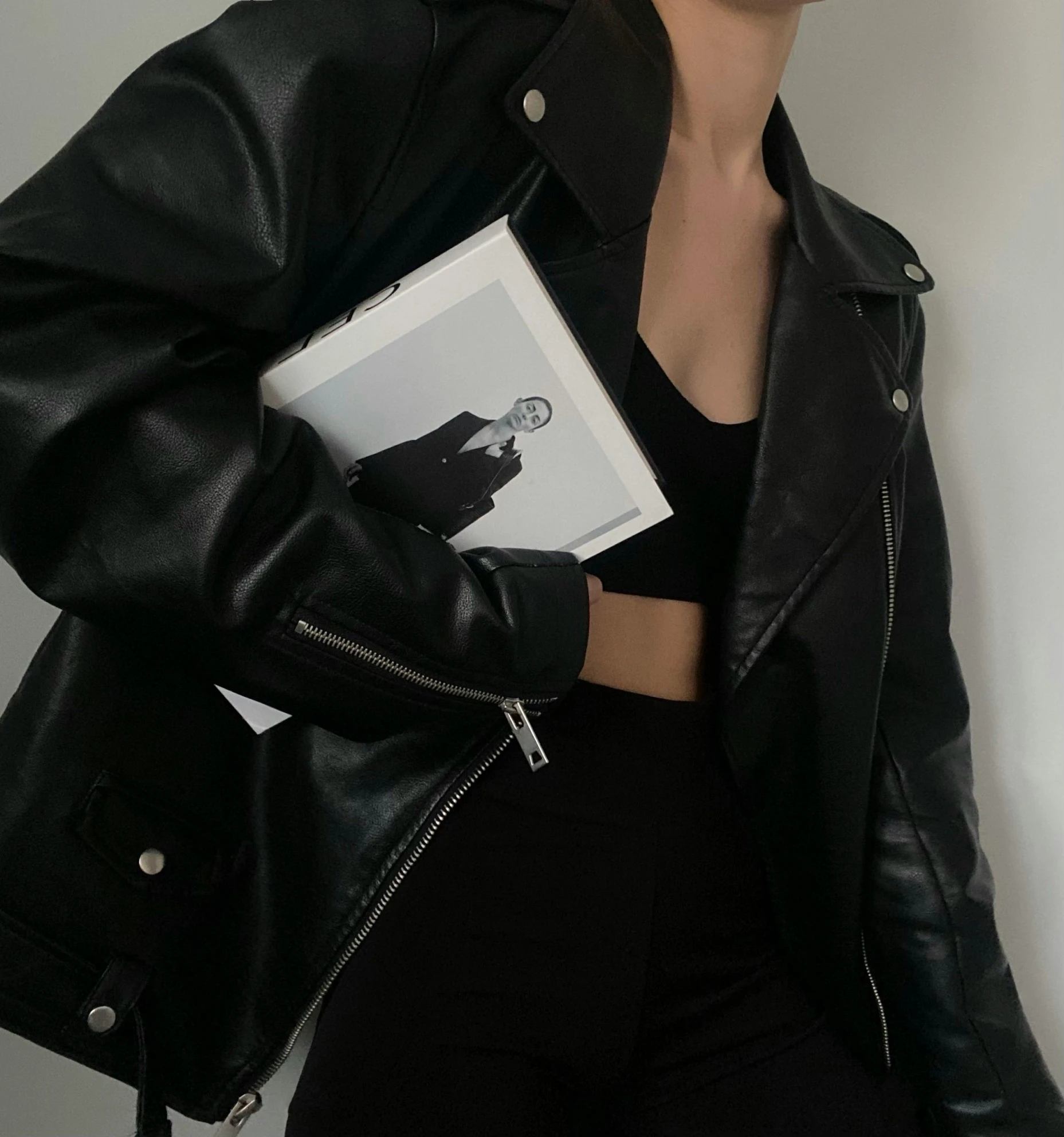 a woman is holding a book wearing black leather jacket and sunglasses