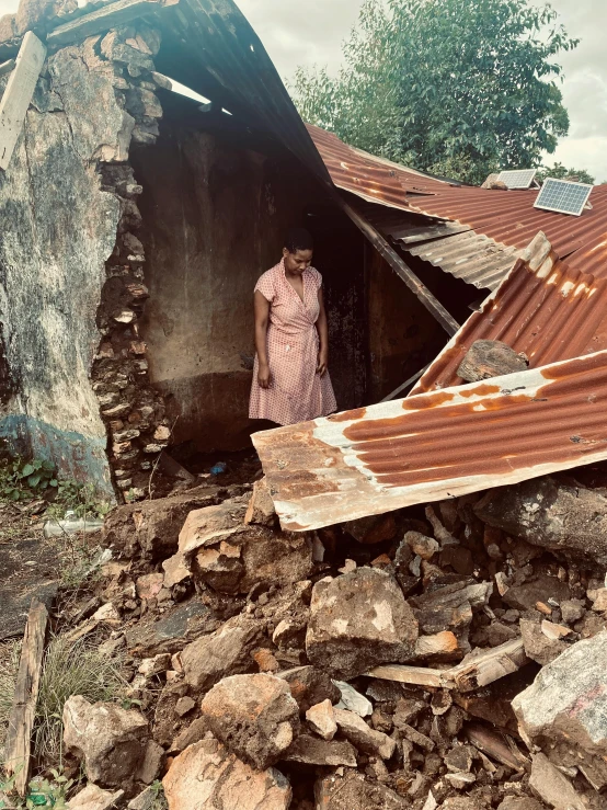 a woman is standing in a doorway with rubble