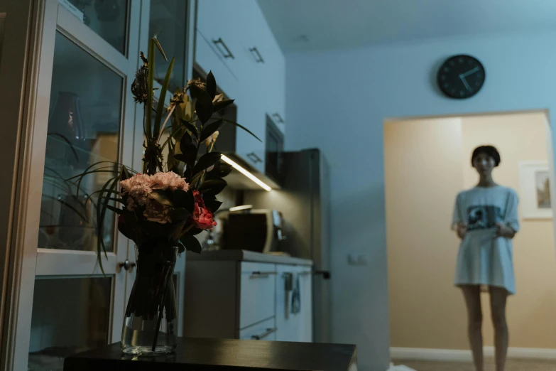 a woman in blue looking at a vase with flowers