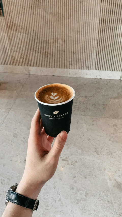 a hand holding a paper coffee cup with a spoon