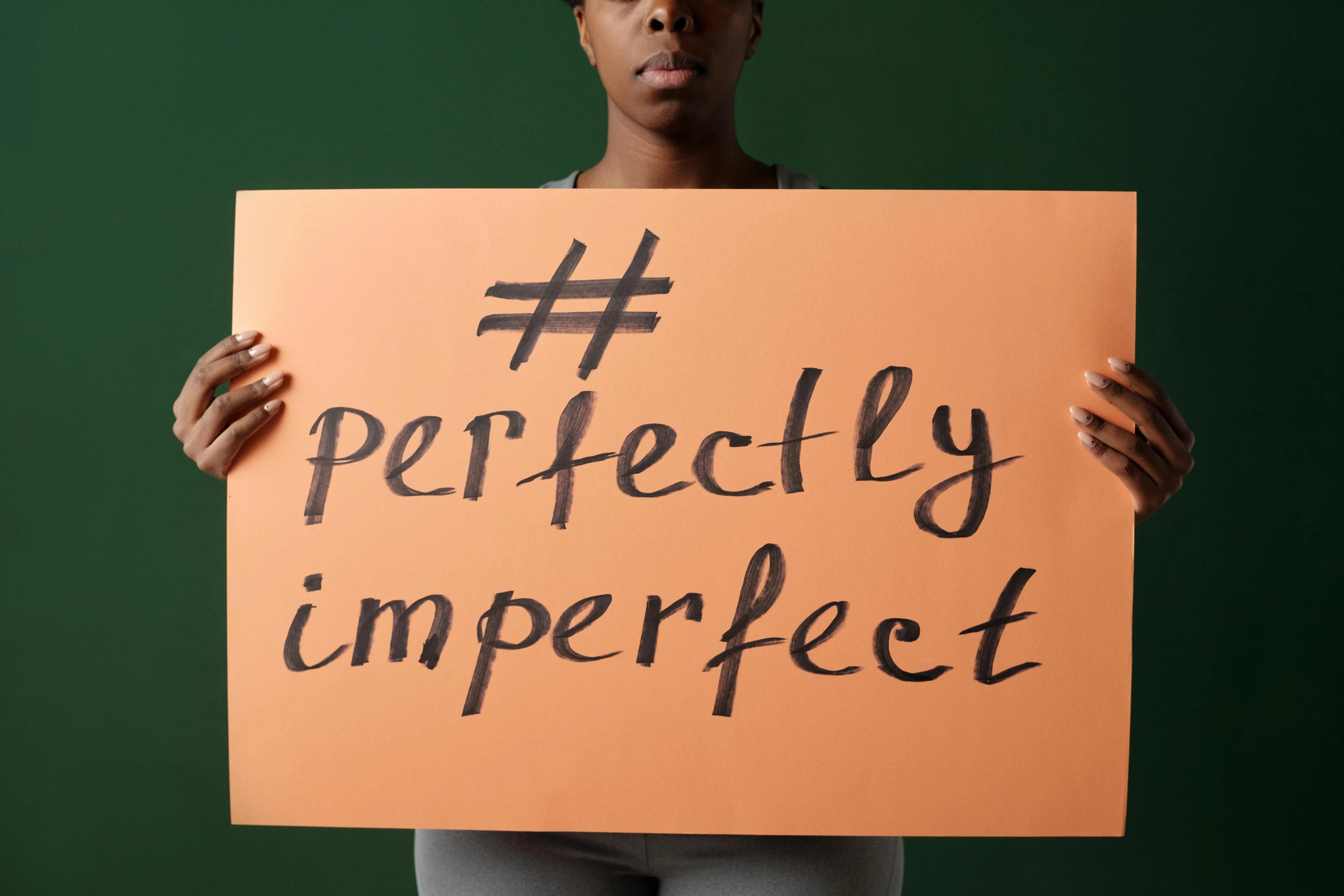 a woman holding up a sign that says perfectly imperfect